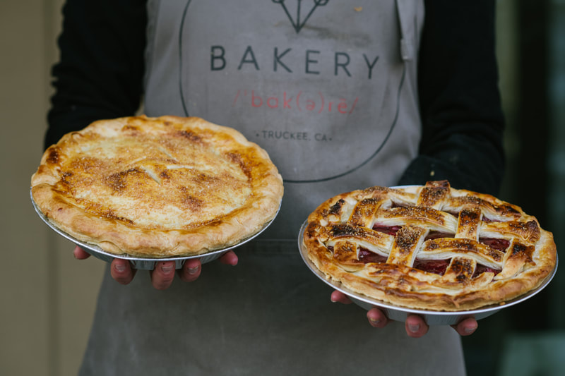 baker holding two kinds of pies